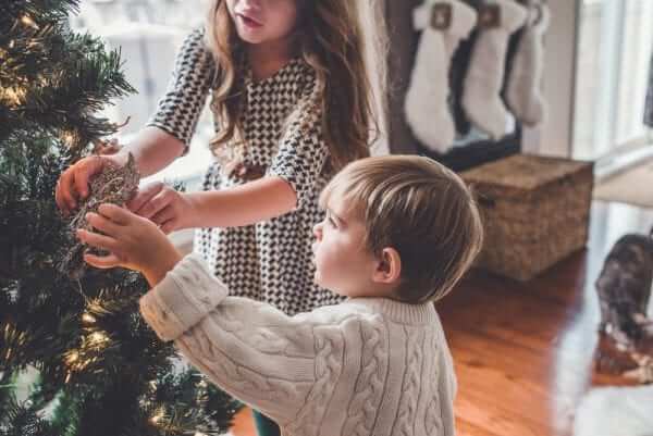 two siblings decorating a christmas tree