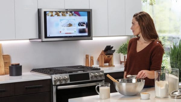A woman making cookie dough while watching a guide from her kitchen TV
