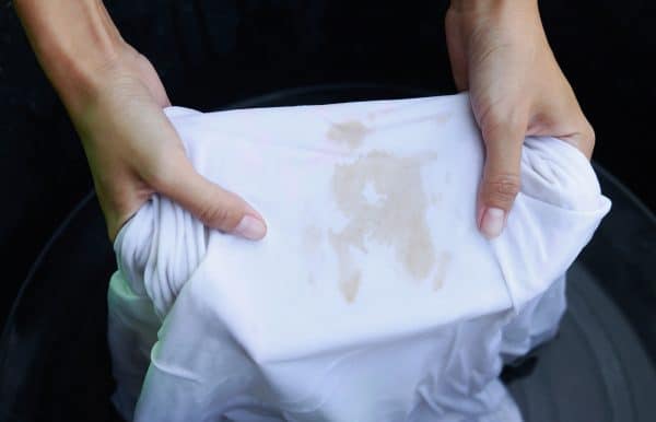 Hands holding a stained white shirt
