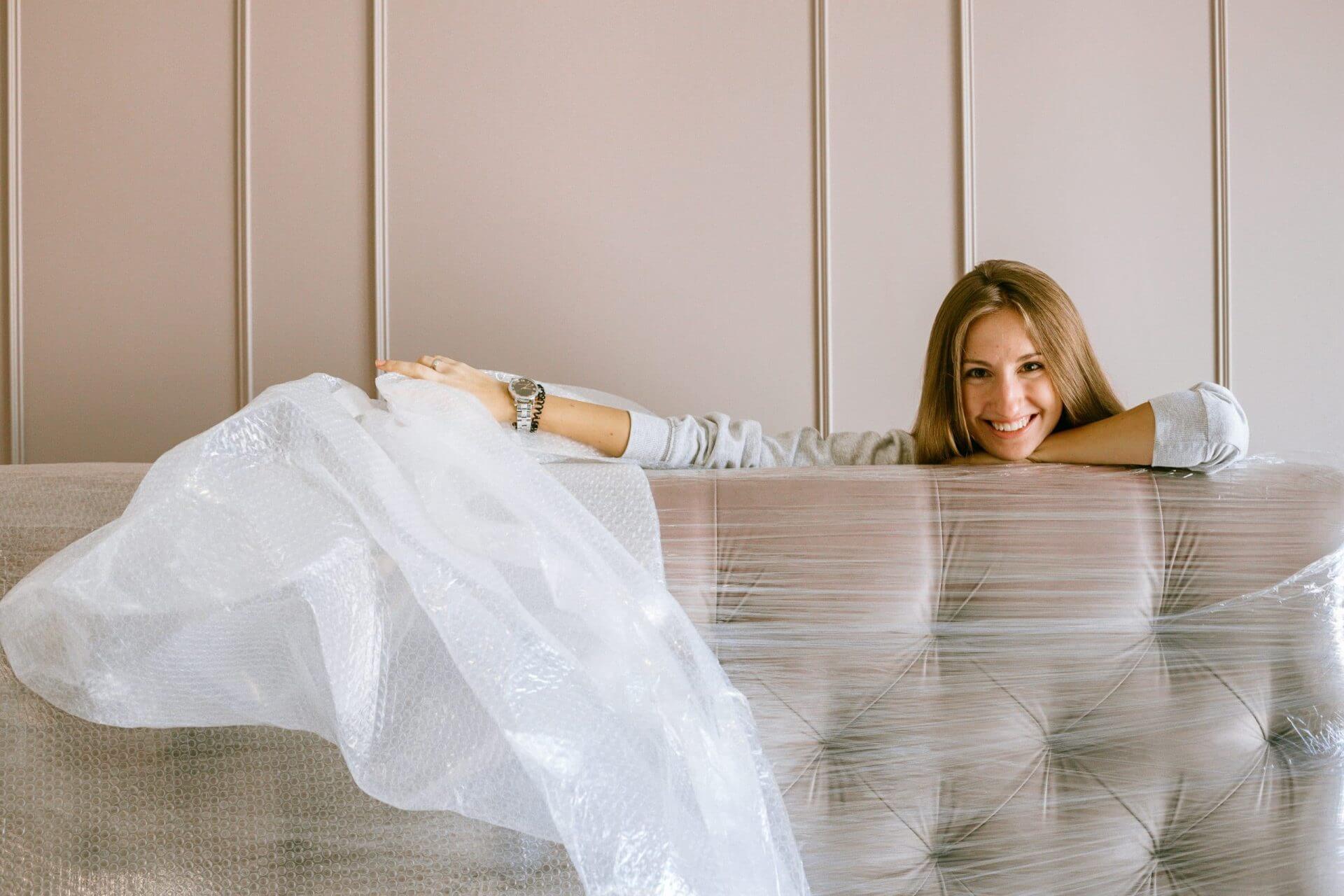 A woman leaning on a couch covered in plastic